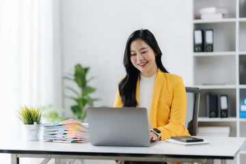 Productive Workplace: A focused individual, illuminated by natural light, skillfully navigates a laptop at a modern desk within a tranquil work environment. 