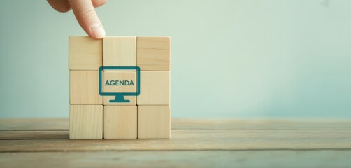 Agenda Focus: A hand meticulously places a cube with 'Agenda' and a computer screen, symbolizing precision and planning. The image is on the cusp of an upcoming meeting