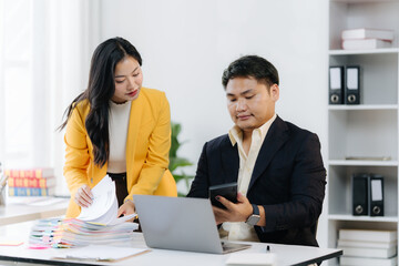 Business Partners in Collaboration: Two professional individuals are immersed in a focused discussion, analyzing documents and data within a modern office setting, signifying collaboration, teamwork.