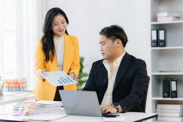 Obraz premium Collaborative Review: Two professionals in a modern office analyze reports, focused and engaged, exemplifying teamwork and productivity.