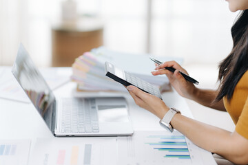 Focused Workflow: A professional concentrates on her task, meticulously reviewing documents and engaging with technology in a contemporary workplace environment.