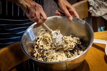 A close up of an unrecognisable woman mixing a Christmas cake with a wooden spoon