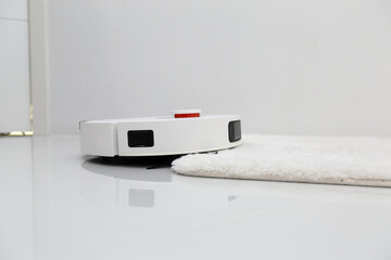 White robotic vacuum cleaner on ceramic floor cleaning