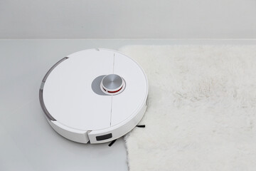 White robotic vacuum cleaner on ceramic floor cleaning