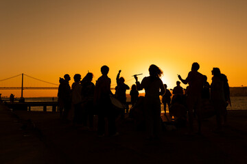 A silhouette - drum players plays music by sticks against a sunset