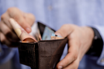 Close-up shot of a person holding a brown leather wallet filled with money, representing financial concepts like budgeting, savings, and wealth.