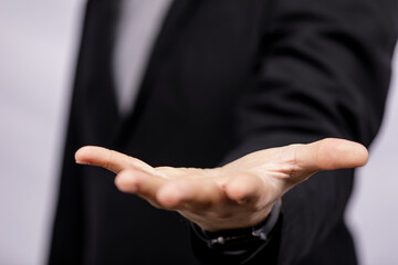 Close-up of a businessman's hand reaching forward. Concept of giving, support, offer, business, deal, help, partnership, or invitation.