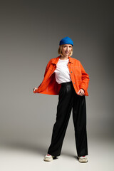 Stylish blonde woman in trendy outfit poses confidently in studio setting