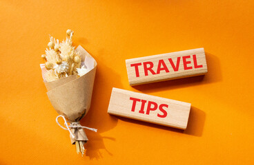 Travel tips symbol. Wooden blocks with words Travel tips. Beautiful orange background. Business and Travel tips concept. Copy space.