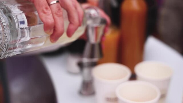Bartender working, beautiful row line of different coloured liquor alcohol cocktails on a open air party in a bar,  catering banquet on event, barman mixing drinks, selection of beverages in club