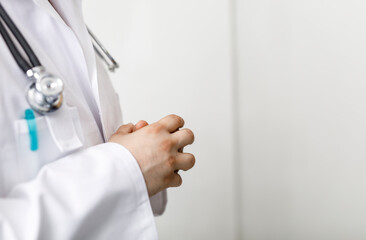 A close-up shot of a doctor wearing a white coat and a stethoscope, with hands clasped, conveying medical expertise and healthcare. Ideal for me