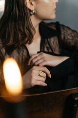 Mysterious woman in black lace poses with a candle in a smoky, gothic setting beside a vintage piano