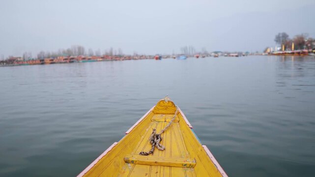 POV shot of Shikara - Boat ride in Dal lake at Srinagar, Kashmir, India. Yellow wooden boat floating in lake during winter season. Travel and holidays concept.