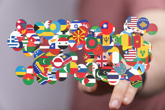 A person's hand touching a collection of country flags, representing global connection, international business, travel and unity across borders.