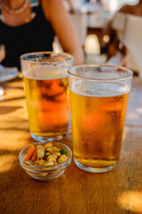 Zwei Biergläser und Snacknüsse auf Holztisch