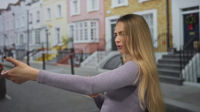 Young woman with long hair playfully mimics pulling rope gesture on a colorful city street portraying fun outdoor activity