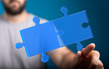 A hand connects two blue puzzle pieces, representing teamwork, partnership, problem-solving, and...