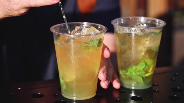 Bartender working, beautiful row line of different coloured liquor alcohol cocktails on a open air party in a bar,  catering banquet on event, barman mixing drinks, selection of beverages in club