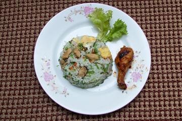 chicken fried rice paired with a perfectly glazed drumstick, beautifully presented on an elegant floral plate. Ideal for food blogs, menus, and culinary inspiration