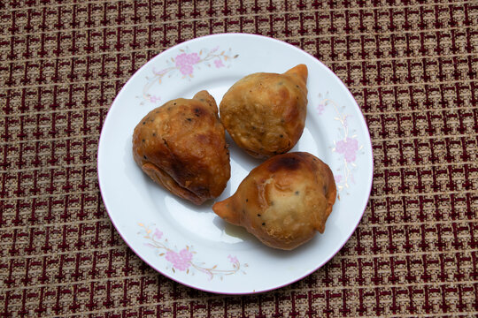 Kolija singara golden samosas elegantly presented on a decorative plate, ideal for tempting any foodie.