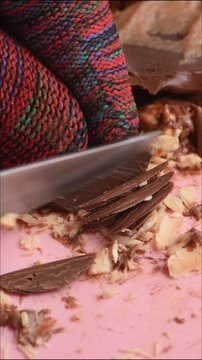 cutting milk chocolate with a knife into small pieces, soft chocolate, cutting smoothly, close-up.