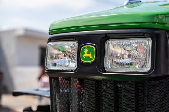 Close up of the John Deere emblem (leaping deer) fixed on the front grille of a bright green tractor. Jalisco, Mexico, Oct. 22, 2025.