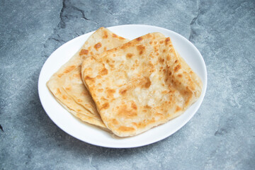Crispy golden plain paratha stacked invitingly on a white plate, perfect for capturing the essence of homemade goodness and delicious, satisfying meals