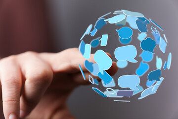 Abstract image of a hand holding a globe shape made of speech bubbles, conveying concepts like...