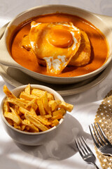 The “Francesinha Especial" traditional from northern Portugal, consists of layers of bread, assorted meats, and melted cheese, served with a hot and slightly spicy sauce.