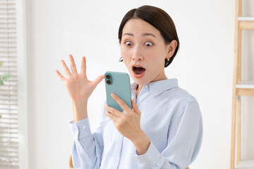 Naklejka premium スマホを持って驚く女性
