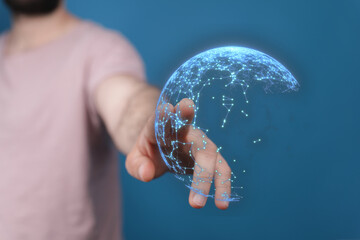 Person's hand touching a digital sphere representing global connection, technology, and network on a blue background. Ideal for tech and future