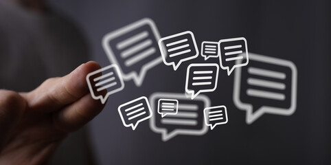 A person's hand holding digital speech bubbles, symbolizing messaging, dialogue, and communication....