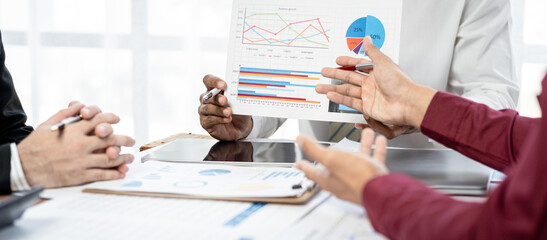 Three people are sitting at a table with a lot of papers and graphs