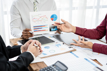 Three people are sitting at a table with a lot of papers and graphs