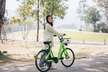 Obraz premium A woman is riding a green bicycle with a basket on the front