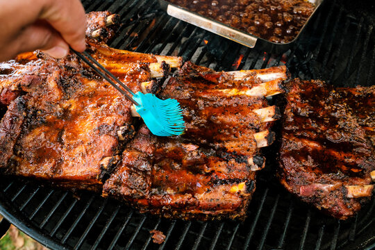ger&auml;ucherte und geschmorte St. Louis Cut Ribs (fleischige Bauchrippen vom Schwein), werden beim Fertiggrillen mit Glasur bepinselt