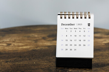 December 2025 calendar monthly page on wooden table background