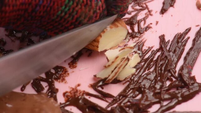 Almonds are cut and crushed with a knife, close-up, to prepare a sweet with a nutty aroma.