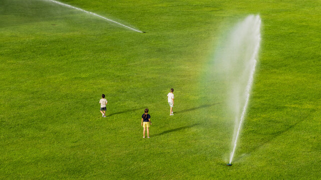 Kids have fun during grass watering. 