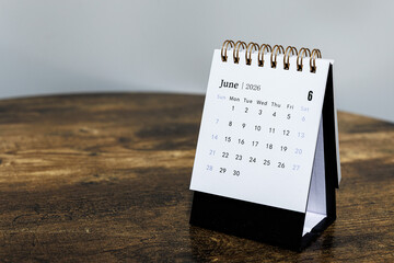 June 2026 monthly calendar page on a wooden desk, minimal design planner representing time management and organization at workplace