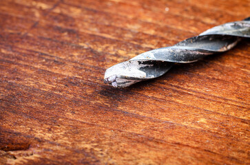 Close-up of a drill bit on a wooden surface, ready for construction work