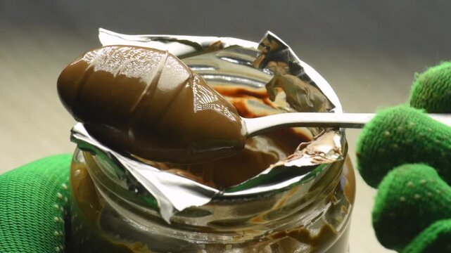 take chocolate cream, put a spoon into a jar of chocolate paste, close-up.