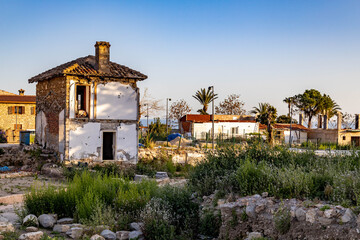 Ruins of an old house near ancient Roman pavement with column fragments, overgrown with grass under...