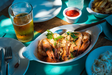 Riesengarnelen in Knoblauchbutter in Servierschale auf gedecktem Tisch © Michael