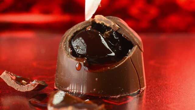 remove cherry from chocolate candy with a knife, cut candy with liqueur and cherry, super macro.