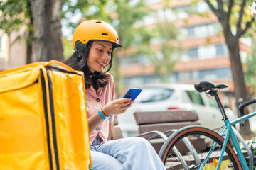 Asian woman delivery rider checking smartphone on break