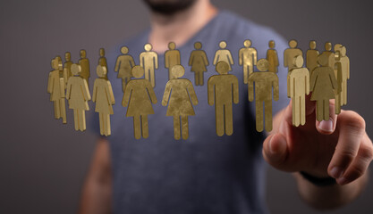 A man's hand touching a group of golden figures representing people. Social media and community concept. Digital life and networking.