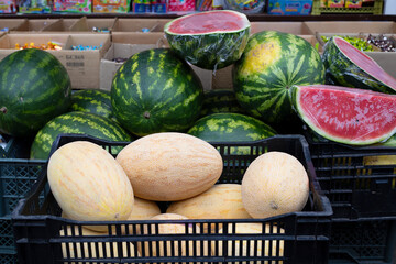 Melons and watermelons in outdoor market stall and juicy red watermelon cut in half.