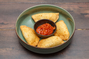 Pastels ouest-africains avec sauce rouge aux oignons maison, présentés sur une assiette colorée. Cuisine sénégalaise. 