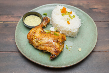 Yassa poulet – poulet mariné aux oignons et citron, plat traditionnel ouest-africain présenté sur une assiette colorée, table en bois. Plat africain. 